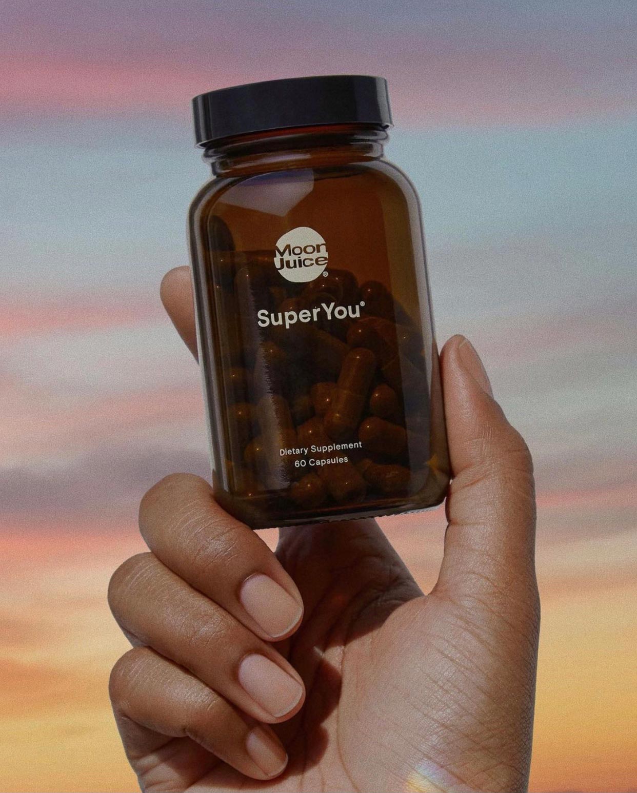 Moon Juice SuperYou Dietary Supplements being held in a sunset