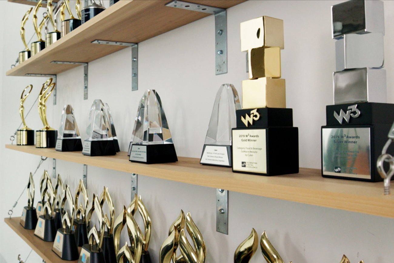 Shelves of Cuker industry awards, including W3 Awards trophies for GoMacro