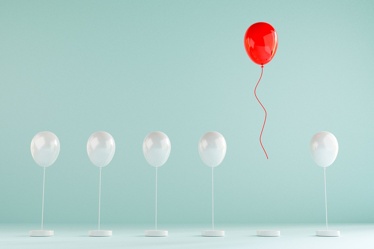 Red balloon rises above white ones, showing how a distinct brand stands out