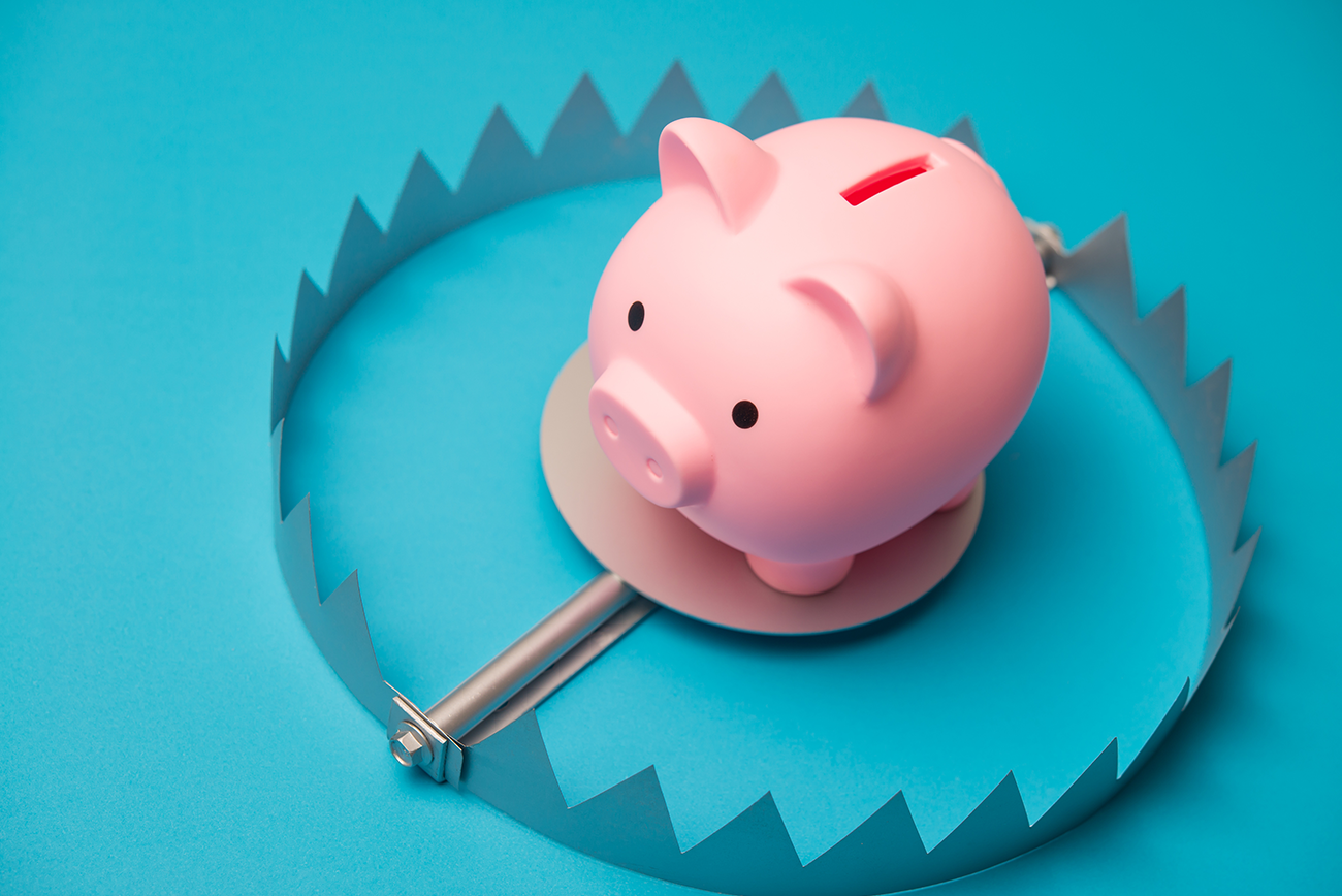 Piggy bank inside a bear trap on blue, symbolizing CPG market share at risk