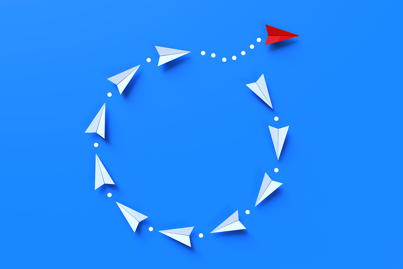 Red paper plane breaking from a circle of white planes, a brand that stands out