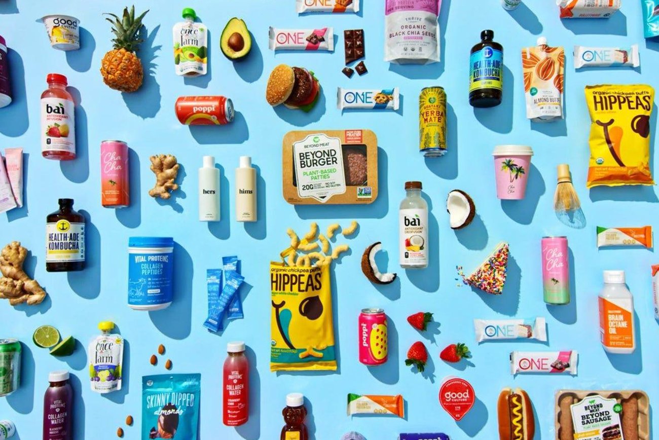 Flat lay of fast-growing CPG brands like Poppi and Hippeas on a blue background