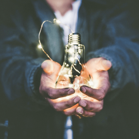 Hands holding light bulb that inspires success and brand growth