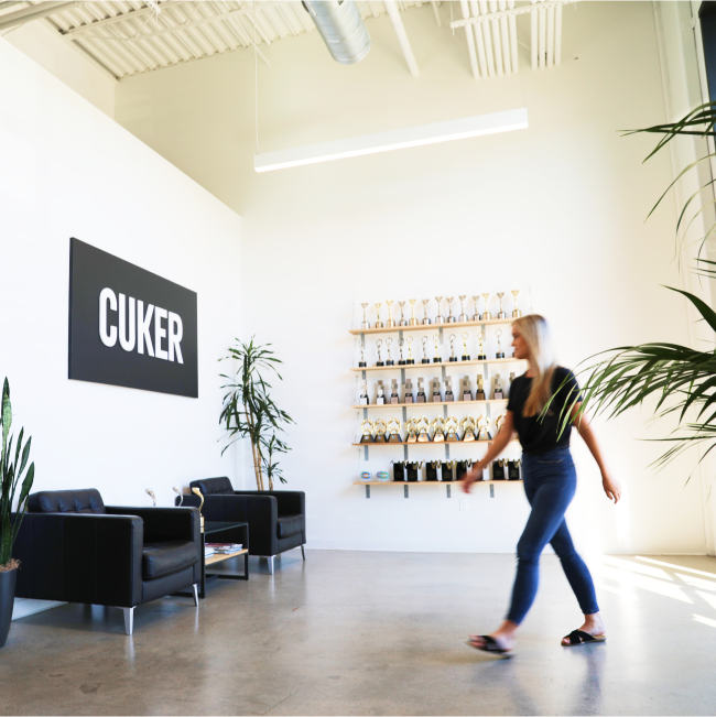 Cuker Team Member Walking Past Trophy Wall in Office Lobby